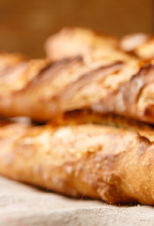 Close-up of two crusty baguettes placed on a cloth surface.