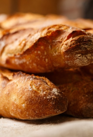 Close-up of two crusty, golden-brown baguettes stacked on a surface.